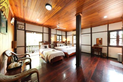 a bedroom with two beds and a wooden ceiling at KhounPhet Hotel in Luang Prabang