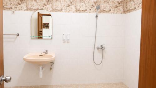 a white bathroom with a sink and a shower at Nakula Familiar Inn in Denpasar