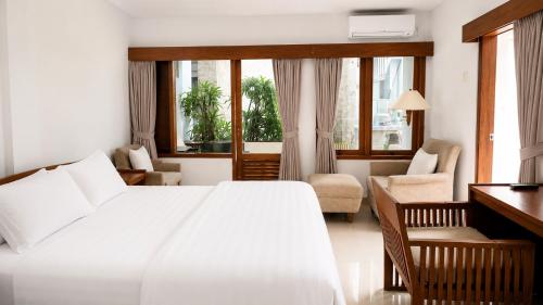 a bedroom with a white bed and a living room at Nakula Familiar Inn in Denpasar