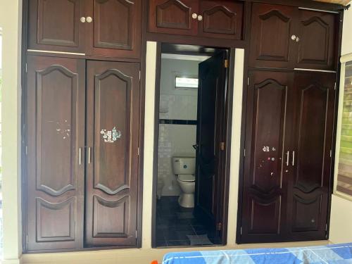 a bathroom with wooden cabinets and a toilet at San Gerónimo Casa Hostal in Mocoa