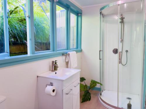 a bathroom with a white sink and a shower at Bach 22 at Palm Beach in Waiheke Island