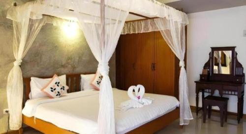 a bedroom with a white bed with a canopy at At home boutique in Ban Long