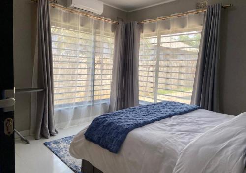 a bedroom with a bed and a large window at Pizzaro Flats 2 in Chongwe