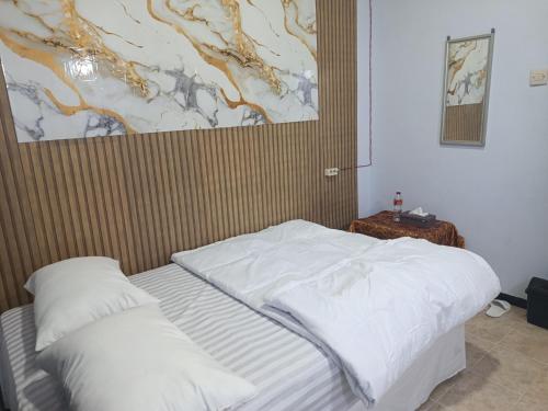 a bedroom with a bed and a painting on the wall at River cliff guest house in Gunungsriti