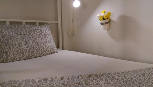 a bedroom with a white bed with a pillow and yellow flowers at Salsa Hostel in Chumphon
