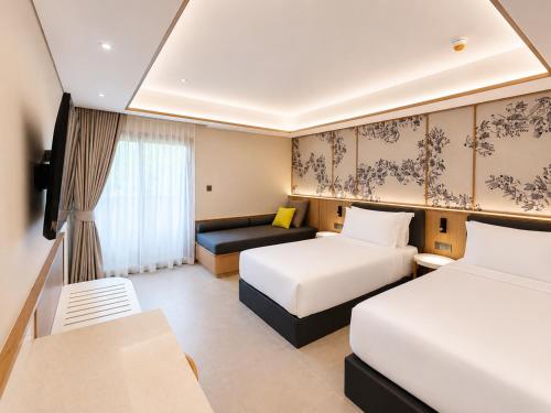 a hotel room with two beds and a couch at Myneris Hotel, Phuket Karon Beach in Karon Beach