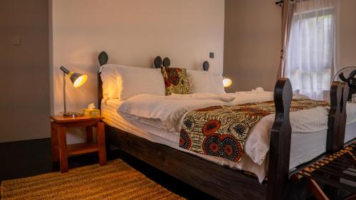a bedroom with a bed and a table with a lamp at Maksoru Spring Lodge in Arusha
