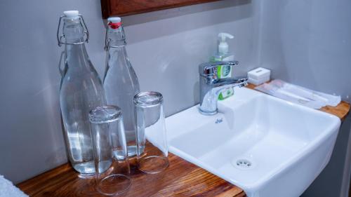 two glass bottles and glasses sitting on a bathroom sink at Maksoru Spring Lodge in Arusha