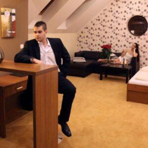 Ein Mann sitzt an einem Schreibtisch in einem Wohnzimmer. in der Unterkunft Hotel Galanta in Galanta
