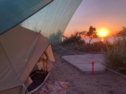 a tent with a sunset in the background at Urban Monkey Summer Camp in Kaji-Say