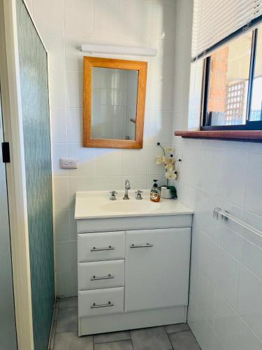 a white bathroom with a sink and a mirror at Sunsethome Wallaroo in Wallaroo