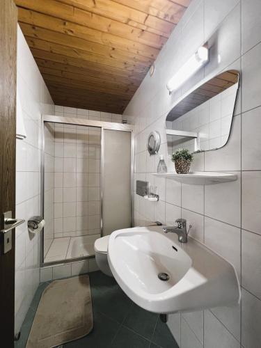a white bathroom with a sink and a shower at Petererhof in Gerlos