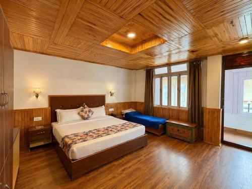 a bedroom with a large bed and a blue couch at Lecoxy Resort in Lachung
