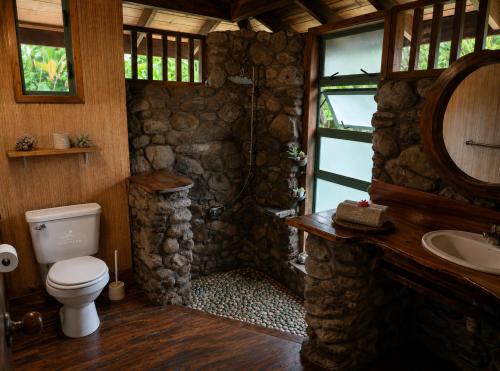 a stone bathroom with a toilet and a sink at Eco Lodge Village Temanoha in Paopao