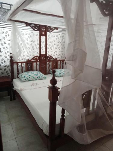 a bed with a canopy with white drapes at Diddy & Eddy's apartment in Malindi