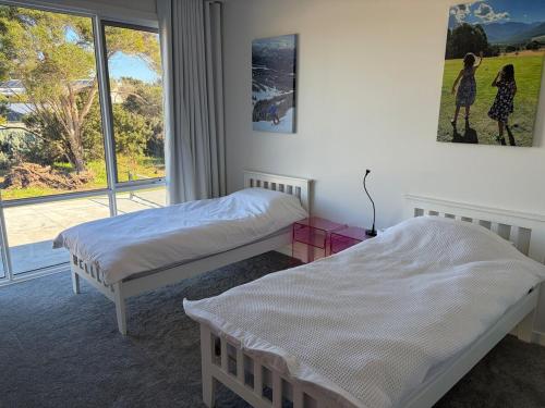 two beds in a room with a window at Tiberius House in Saint Andrews Beach