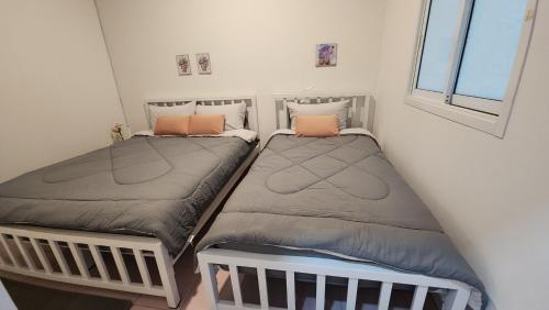 two twin beds in a room with a window at 338 House in Ban Liam