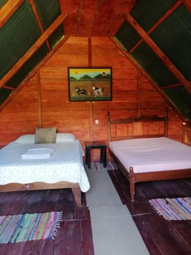 a bedroom with two beds in a wooden cabin at Sunset Inn Arenal B&B in El Castillo de La Fortuna