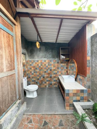 a bathroom with a toilet and a sink at Arta Wooden House in Sukawati