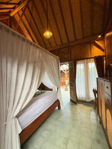 a bedroom with a bed with a mosquito net at Arta Wooden House in Sukawati