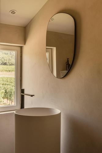a bathroom with a round mirror on the wall at Maison Meraka - Design Guest House of Saint Emilion in Saint-Laurent-des-Combes