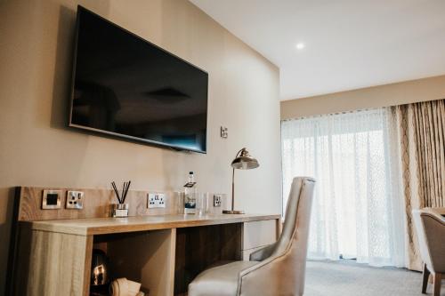 a living room with a desk with a television and a chair at Moddershall Oaks Country Spa Retreat in Stone