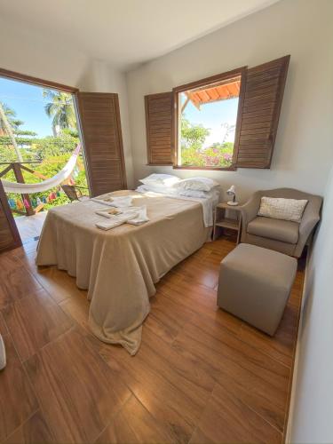 a bedroom with a bed and a chair and a window at Pousada Vila dos Santos in Porto De Galinhas