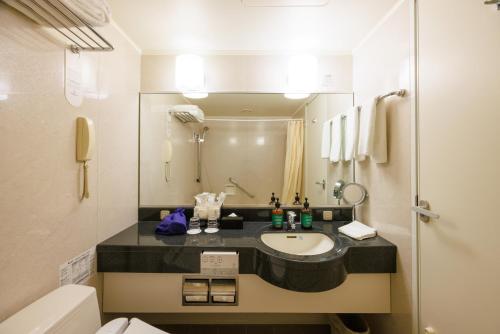 a bathroom with a sink and a toilet and a mirror at ANA Crowne Plaza Yonago by IHG in Yonago