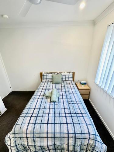 a bedroom with a bed with a blue plaid blanket at Stylish place in Loganlea in Loganlea