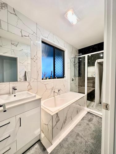 a white bathroom with a sink and a tub at Stylish place in Loganlea in Loganlea