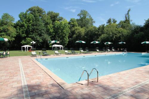 a large swimming pool with chairs and umbrellas at Hotel Villa Luppis in Pasiano di Pordenone