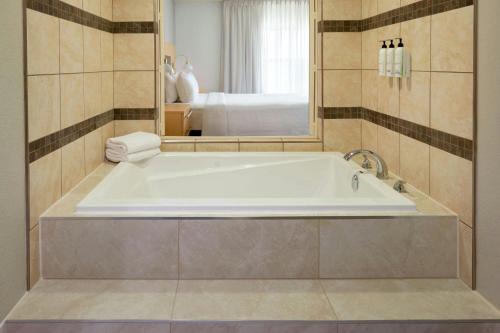 a bath tub in a bathroom with a mirror at TownePlace Suites by Marriott Thunder Bay in Thunder Bay
