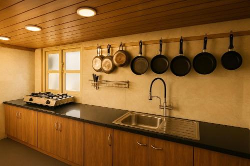 a kitchen with a sink and pots and pans on the wall at Secret Escape Colonial Bungalow in Ooty
