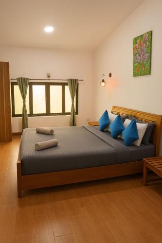 a bedroom with a large bed with blue pillows at Secret Escape Colonial Bungalow in Ooty