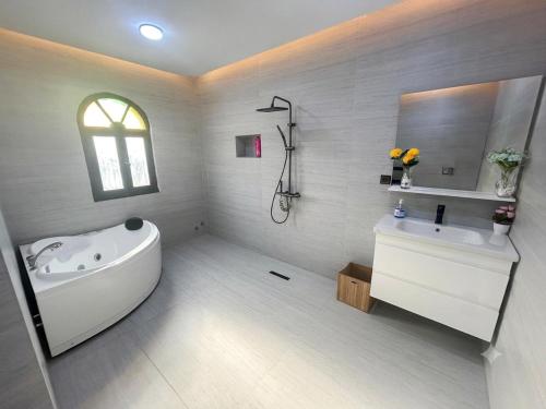 a white bathroom with a tub and a sink at Villa TAHA piscine jacuzzi clim in Martil