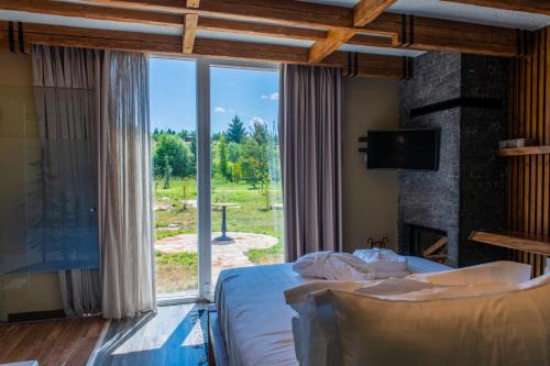 a bedroom with a bed and a large window at Ura e Kovacit Resort & Agrotourism in Voskopojë