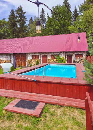a pool in front of a house with a red roof at Gajówka na Roztoczu in Lubycza Królewska