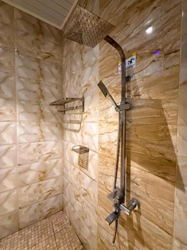 a shower in a bathroom with a stone wall at Chevilly Resort & Camp in Bogor
