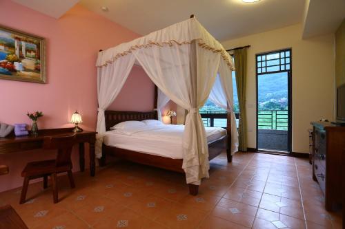 a bedroom with a canopy bed and a desk at Qian B&B in Jiamin