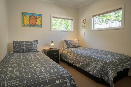 two beds in a room with two windows at Brougham Street B and B in Nelson