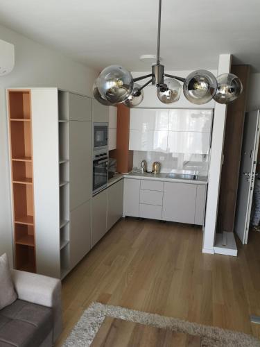 a large kitchen with white cabinets and a chandelier at AH Home Delux Centar in Sarajevo
