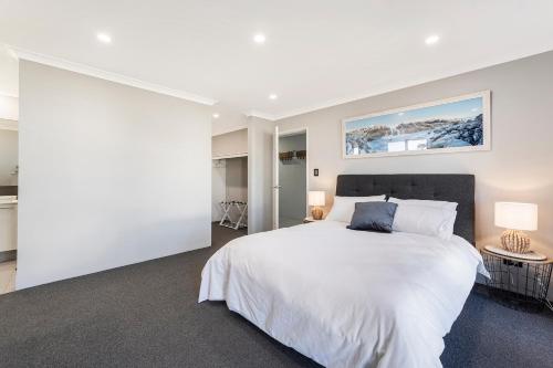 a white bedroom with a large bed and two lamps at Your Beach Getaway in Singleton