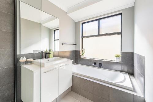 a bathroom with a tub and a sink and a window at Your Beach Getaway in Singleton