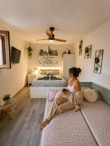 a woman sitting on a couch in a bedroom at La Petite Finca in Elche