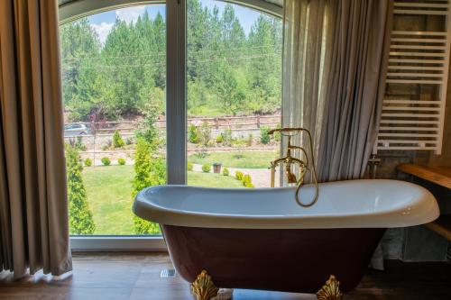 a bath tub in a bathroom with a large window at Ura e Kovacit Resort & Agrotourism in Voskopojë