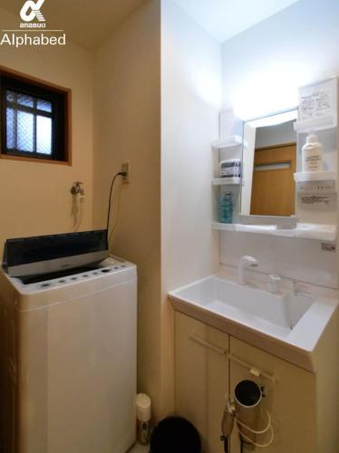 a small kitchen with a sink and a washer at Alphabed松山城西 in Matsuyama