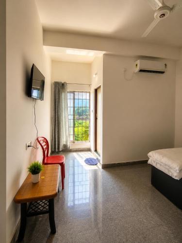a room with a bed and a table and a chair at White Lily in Guwahati