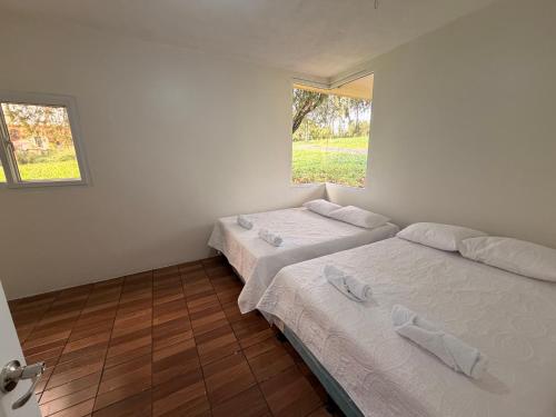 two beds in a white room with a window at Dormilón in San Felipe