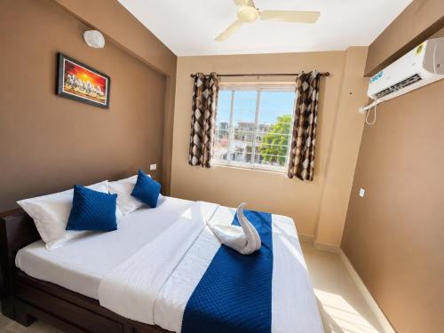 a bedroom with a bed with blue pillows and a window at Casafern Homestay Goa in Varca