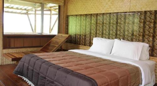 a bedroom with a bed and a chair and a window at Phucome Resort in Campson